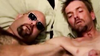 Mature duo in bed tugging together